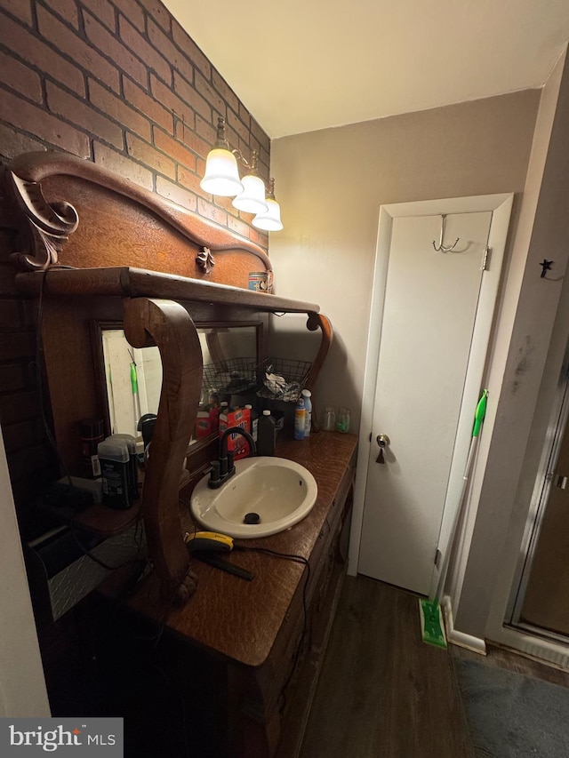 bathroom with vanity, hardwood / wood-style floors, and brick wall