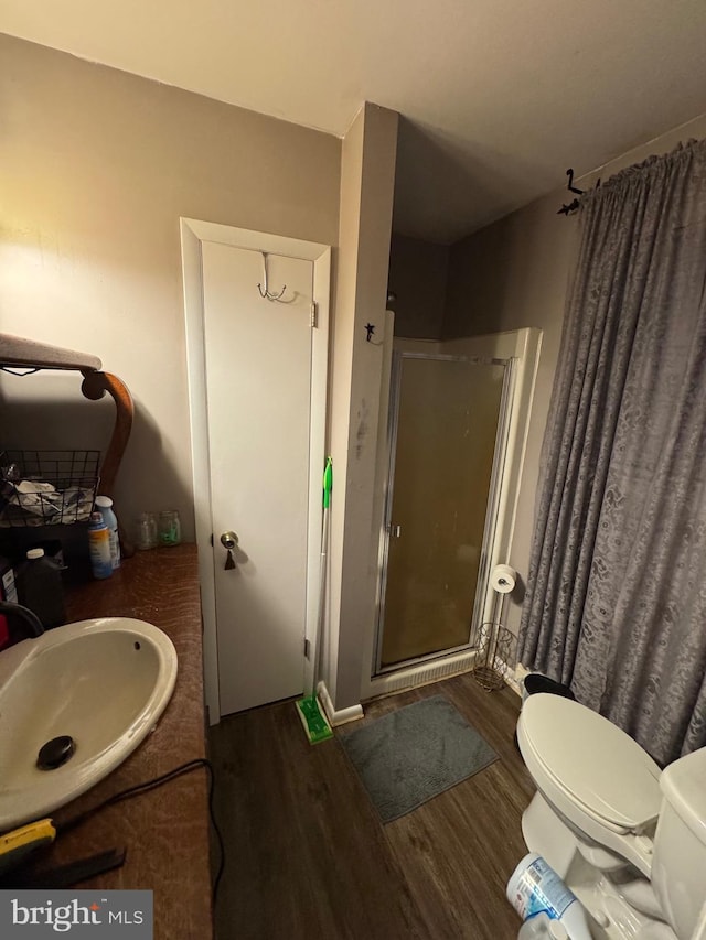 bathroom featuring hardwood / wood-style flooring, vanity, toilet, and a shower with shower door