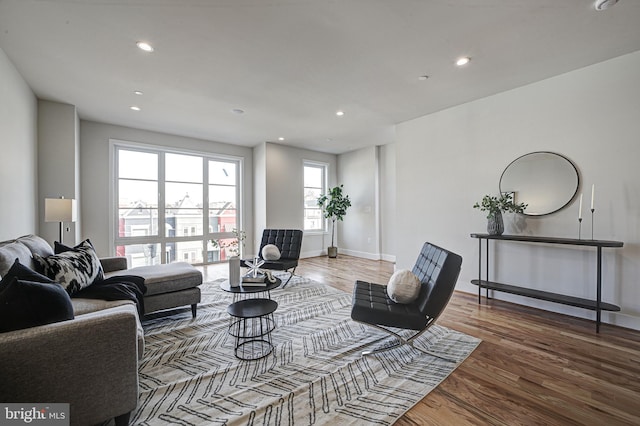 living area with baseboards, wood finished floors, and recessed lighting