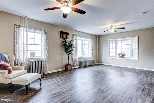 sitting room featuring dark hardwood / wood-style floors, radiator heating unit, and ceiling fan