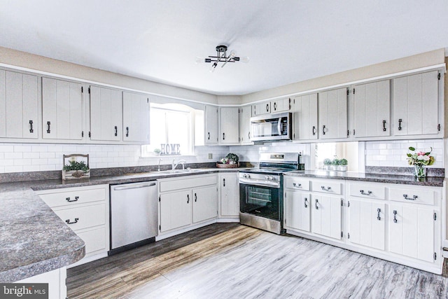 kitchen featuring appliances with stainless steel finishes, sink, light hardwood / wood-style floors, and decorative backsplash