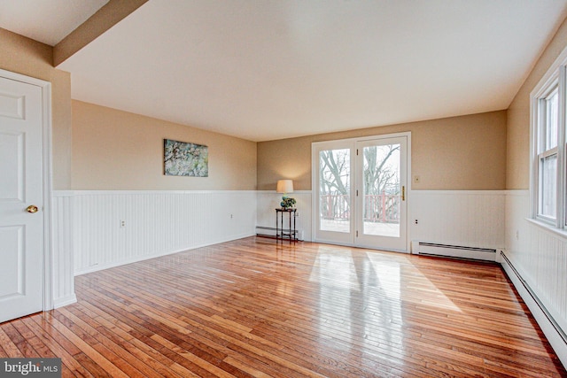 empty room featuring light wood-type flooring and a baseboard heating unit