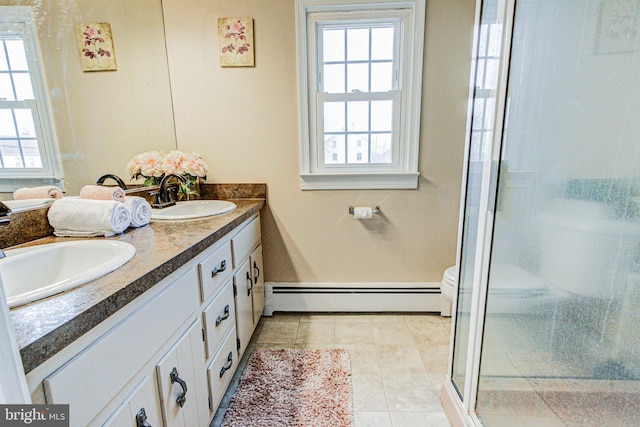 bathroom with a baseboard radiator, vanity, a shower with shower door, and plenty of natural light