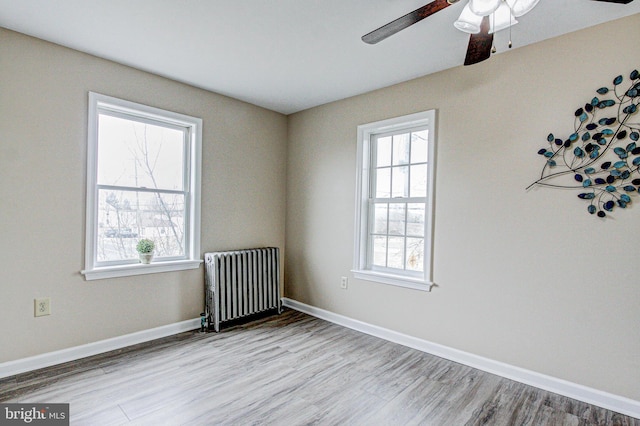 empty room featuring radiator, hardwood / wood-style flooring, and ceiling fan