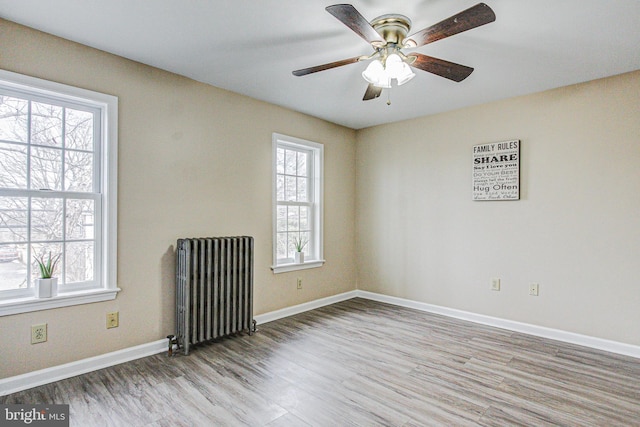 unfurnished room featuring radiator, ceiling fan, and light hardwood / wood-style floors