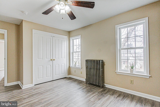 unfurnished bedroom with multiple windows, a closet, and radiator heating unit