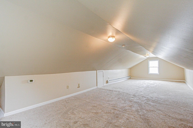 bonus room with a baseboard heating unit, light carpet, and vaulted ceiling