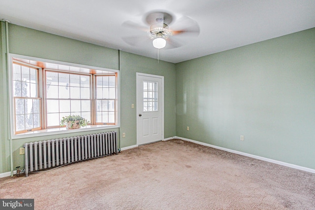 empty room with radiator heating unit, ceiling fan, and light colored carpet