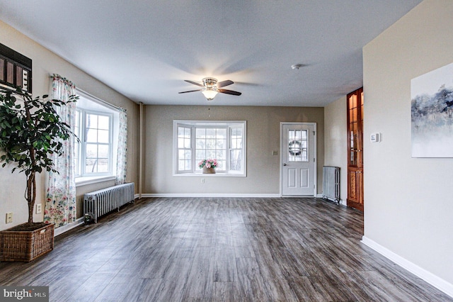 unfurnished living room featuring dark hardwood / wood-style floors, radiator heating unit, and ceiling fan