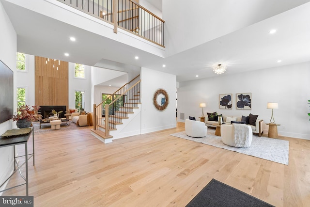 living room with a large fireplace, light hardwood / wood-style floors, and a high ceiling