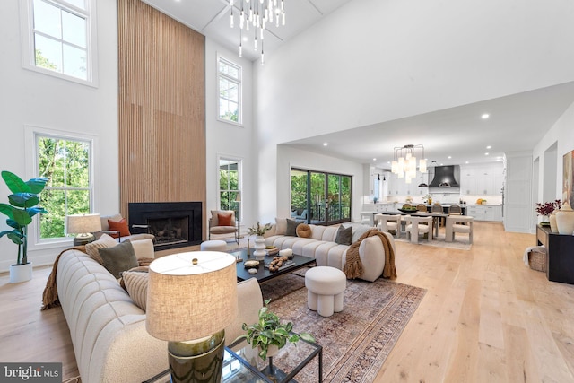 living room featuring a healthy amount of sunlight, light hardwood / wood-style floors, a large fireplace, and a chandelier