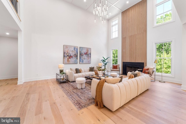 living room with a notable chandelier, plenty of natural light, a fireplace, and light wood-type flooring