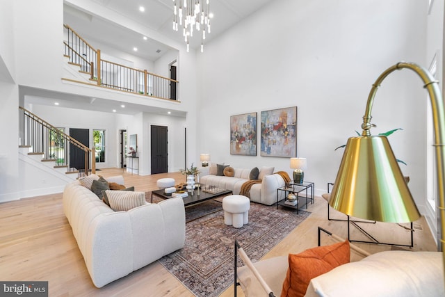 living room with a high ceiling, an inviting chandelier, and light hardwood / wood-style flooring