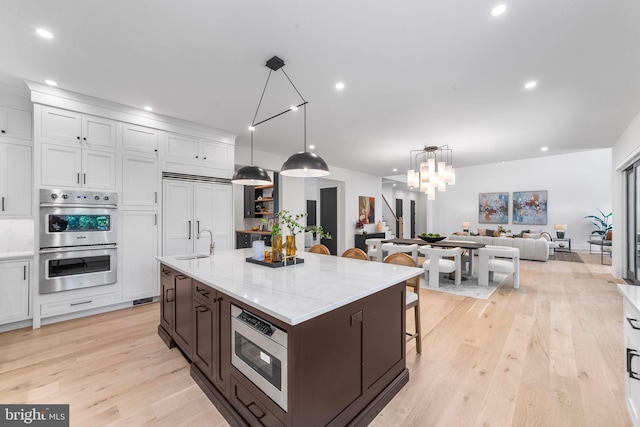 kitchen featuring white cabinetry, sink, built in appliances, and a large island