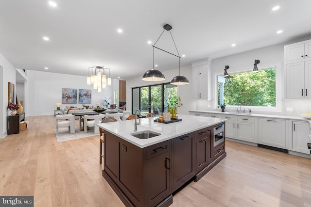 kitchen featuring hanging light fixtures, white cabinetry, sink, and stainless steel microwave