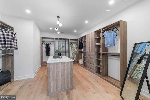 walk in closet with light hardwood / wood-style flooring