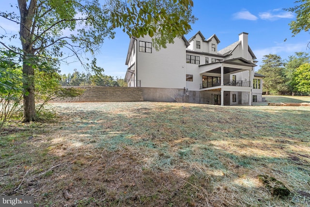 back of property featuring a balcony and a yard