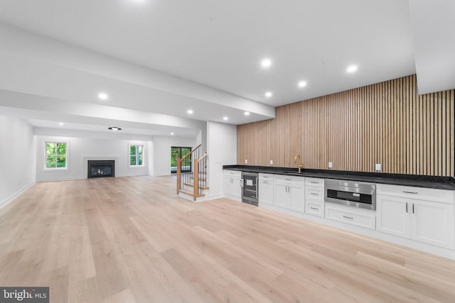 bar with sink, white cabinetry, wine cooler, oven, and light wood-type flooring