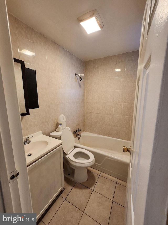 full bathroom with tiled shower / bath, tile walls, tile patterned flooring, vanity, and toilet