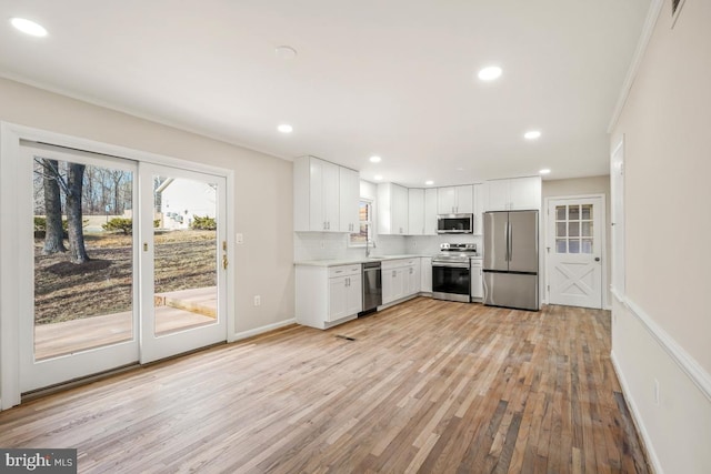 kitchen with decorative backsplash, light hardwood / wood-style floors, stainless steel appliances, and white cabinets