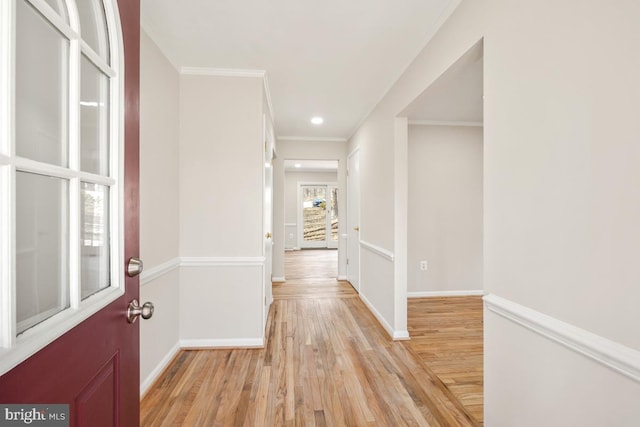 corridor with ornamental molding and light hardwood / wood-style floors