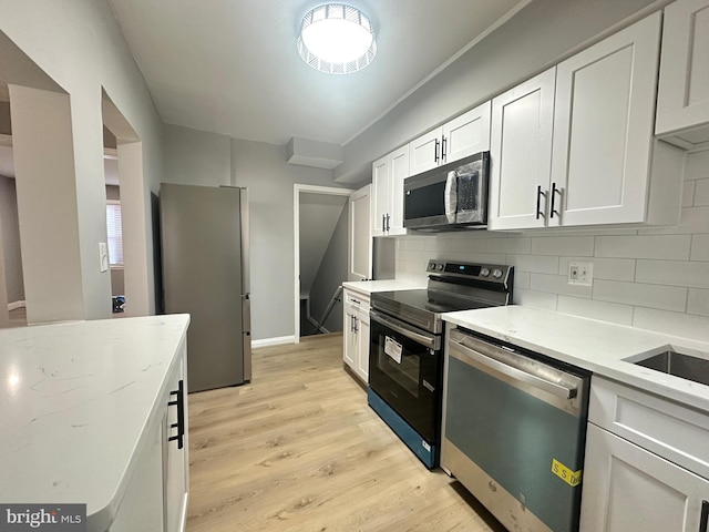 kitchen featuring stainless steel appliances, light hardwood / wood-style flooring, backsplash, light stone counters, and white cabinets