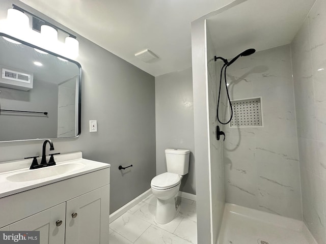 bathroom with vanity, a tile shower, and toilet