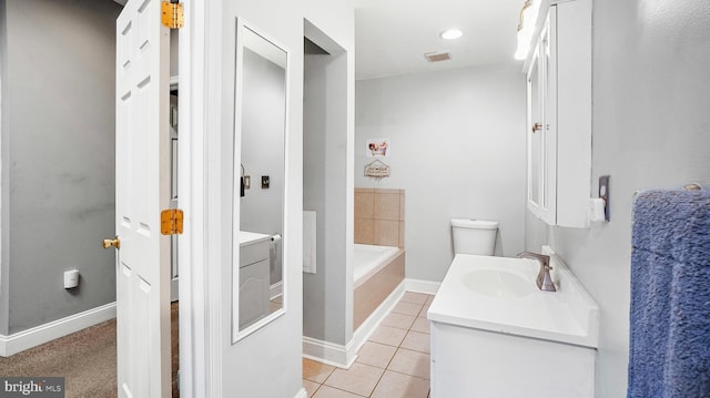 bathroom featuring vanity, a relaxing tiled tub, tile patterned floors, and toilet