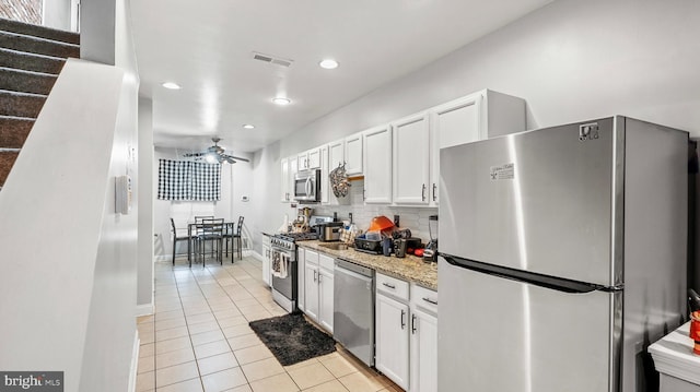 kitchen featuring tasteful backsplash, white cabinetry, light tile patterned floors, light stone counters, and stainless steel appliances