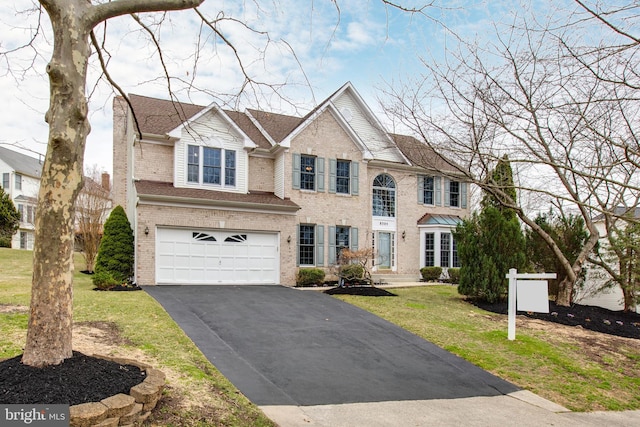 view of front of house with a front lawn, a garage, brick siding, and aphalt driveway