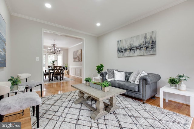 living room with light wood-type flooring, a notable chandelier, and crown molding