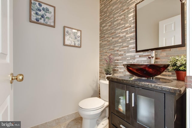 bathroom with tile patterned floors, toilet, decorative backsplash, baseboards, and vanity