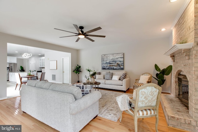 living area featuring visible vents, ceiling fan, light wood-type flooring, recessed lighting, and a fireplace