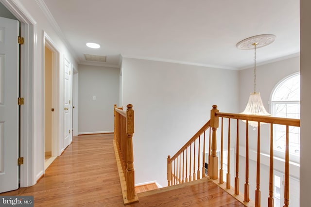 corridor featuring visible vents, an upstairs landing, light wood-style flooring, ornamental molding, and baseboards