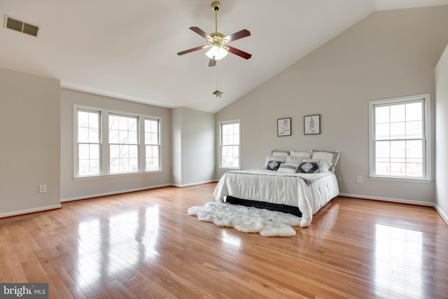 bedroom with baseboards, visible vents, high vaulted ceiling, light wood-style flooring, and ceiling fan