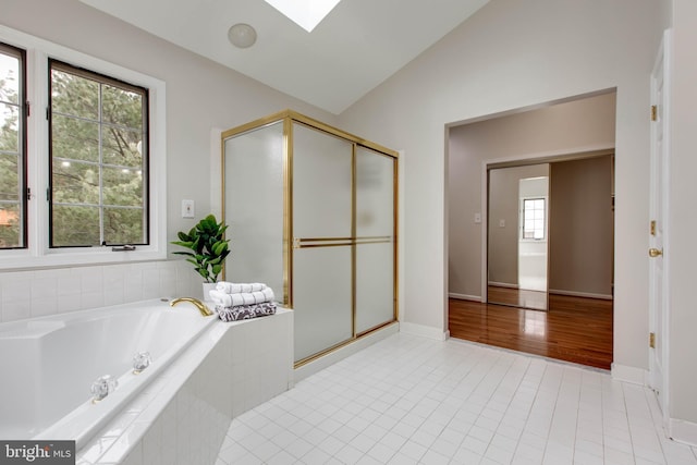 full bath featuring tile patterned floors, lofted ceiling with skylight, a garden tub, and a shower stall