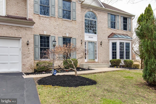 view of front of home with a garage, brick siding, and a front yard