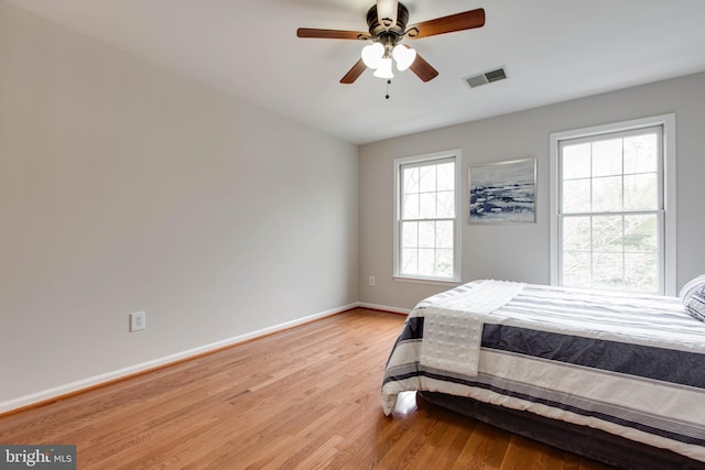 bedroom featuring a ceiling fan, light wood-style flooring, baseboards, and visible vents