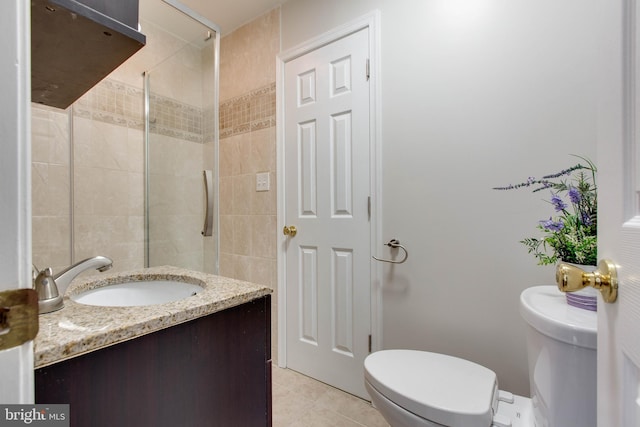 full bath with tile patterned flooring, tiled shower, toilet, and vanity