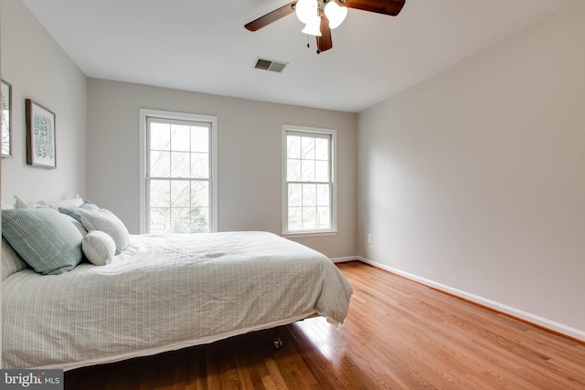 bedroom featuring ceiling fan, wood finished floors, visible vents, and baseboards