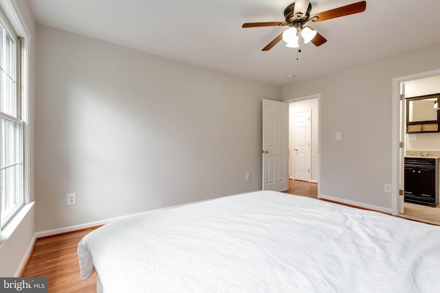 bedroom featuring light wood-style flooring, ensuite bathroom, baseboards, and ceiling fan