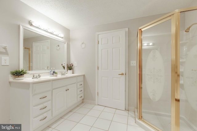 bathroom with tile patterned floors, a shower stall, a textured ceiling, and a sink