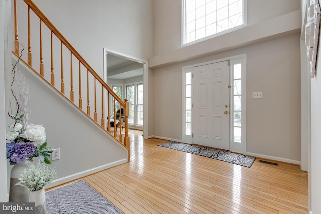 entrance foyer featuring visible vents, a high ceiling, baseboards, and hardwood / wood-style floors