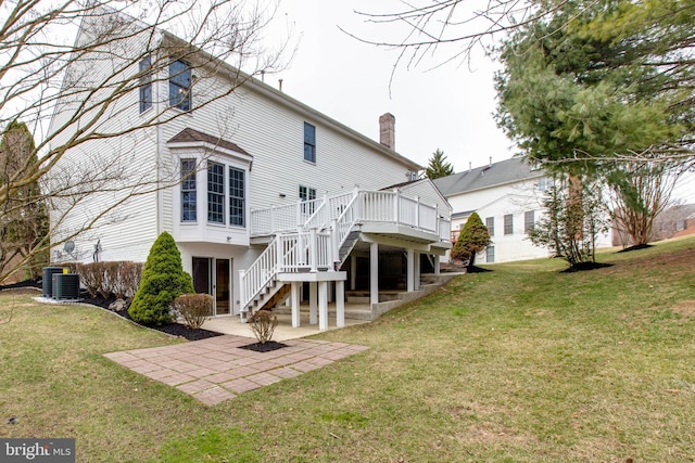 back of property with a deck, stairway, a patio area, and a lawn