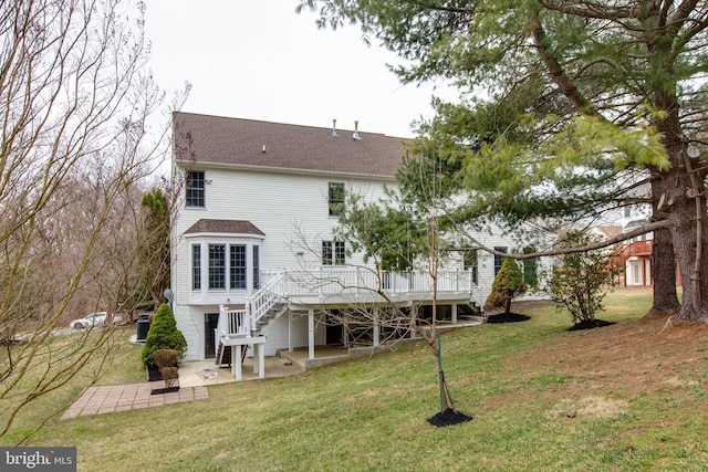 rear view of house featuring roof with shingles, a yard, stairs, a deck, and a patio area