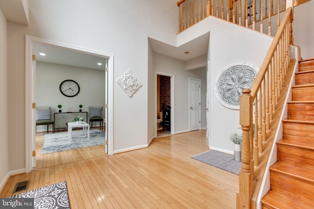 entrance foyer featuring hardwood / wood-style floors, a high ceiling, baseboards, and visible vents