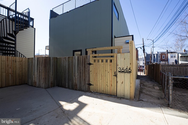 view of property exterior featuring a gate, stairway, and fence