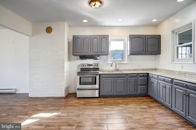 kitchen with light wood-style floors, a baseboard radiator, under cabinet range hood, gray cabinetry, and stainless steel range with electric stovetop