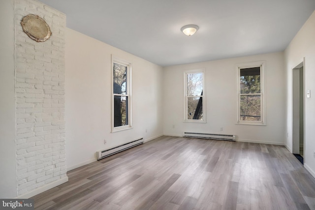 spare room with baseboards, baseboard heating, and wood finished floors