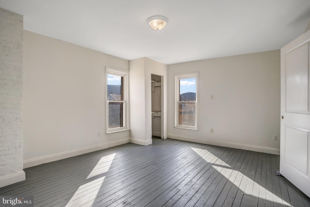 unfurnished bedroom featuring a closet, dark wood finished floors, and baseboards